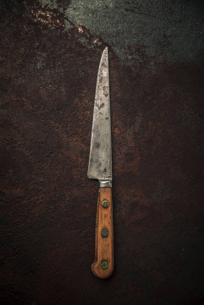Paslı metal desen arka planının üzerinde karbon çelik bıçak ve ahşap saplı vintage küçük kullanım bıçağı düz yatıyordu - Fotoğraf, Görsel