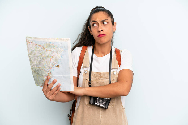 hispanic woman shrugging, feeling confused and uncertain. tourist with a map - 写真・画像