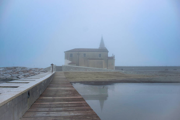 Μια άποψη του χειμώνα της εκκλησίας της Madonna dell 'Angelo στο Caorle, Ιταλία, περιβάλλεται από ομίχλη - Φωτογραφία, εικόνα