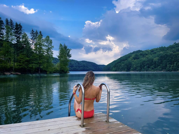 Mujer rubia en bikini rojo cerca del lago en verano - Foto, imagen