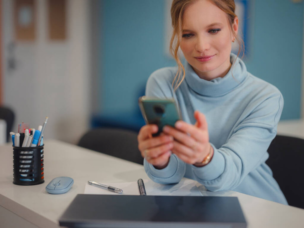 Business woman working in office. Online business, young professional in workplace. communicating with colleagues via messenger on smartphone, or using apps. Female entrepreneur sending text message. - Photo, Image