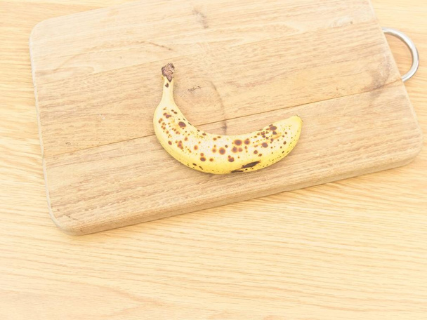 banana biologica matura e tagliere di legno su un tavolo - Foto, immagini