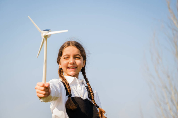 Hraní dětí a vypadá to, že se zajímá o hračku s větrnou turbínou - Koncept budoucí generace a obnovitelné energie - Fotografie, Obrázek