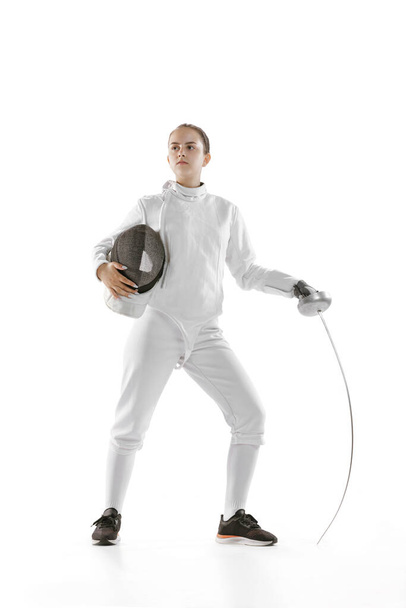 Champion. Portrait of young charming girl, fencer in white fencing costume posing with rapier isolated on white background. Sport, youth, hobbies, achievements, goal. - Photo, Image