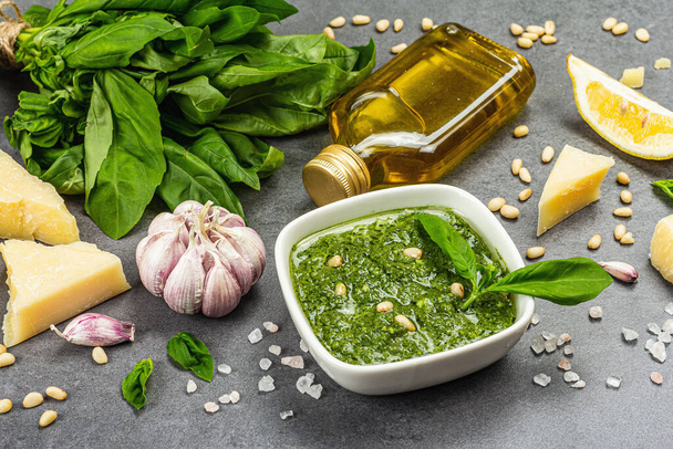 Pesto sauce in a bowls with pine nuts, parmesan and garlic. Traditional Italian food, grey stone concrete background, banner format, close up - Foto, Bild