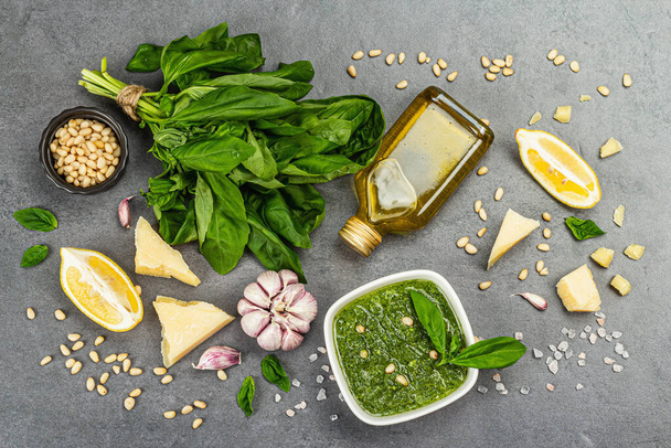 Pesto sauce in a bowls with pine nuts, parmesan and garlic. Traditional Italian food, grey stone concrete background, banner format, top view - Valokuva, kuva