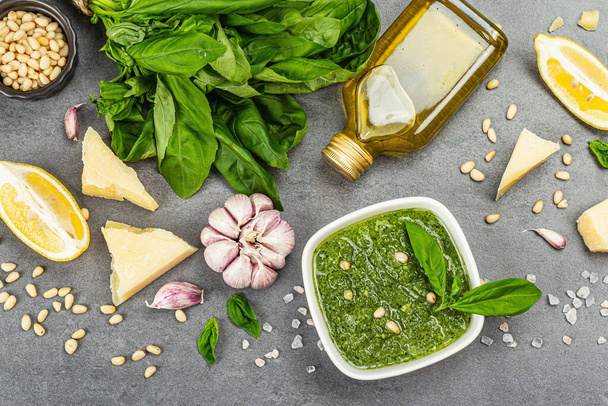 Pesto sauce in a bowls with pine nuts, parmesan and garlic. Traditional Italian food, grey stone concrete background, banner format, top view - Foto, Bild