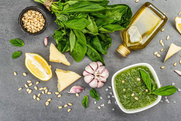 Pesto sauce in a bowls with pine nuts, parmesan and garlic. Traditional Italian food, grey stone concrete background, banner format, top view - Fotografie, Obrázek