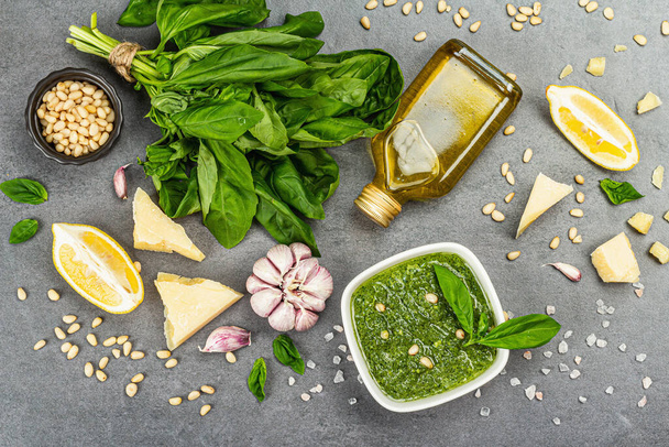 Pesto sauce in a bowls with pine nuts, parmesan and garlic. Traditional Italian food, grey stone concrete background, banner format, top view - Zdjęcie, obraz