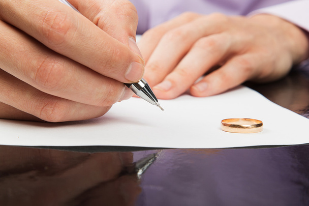 lähikuva miehen kädestä allekirjoittamassa avioeropapereita
  - Valokuva, kuva