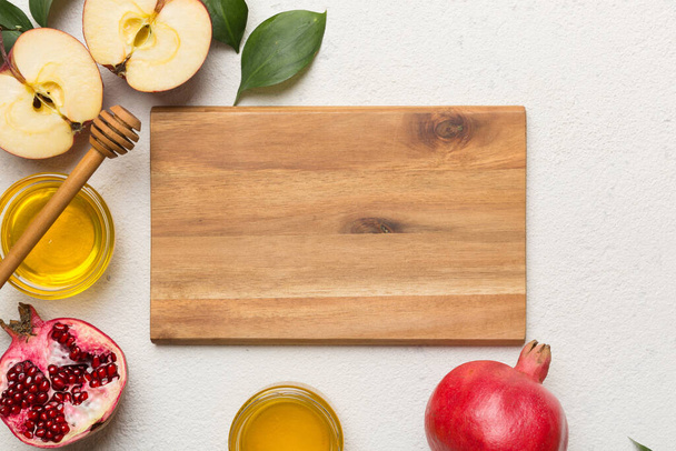 Rosh hashanah, joodse vakantie, concept: honing, appel en granaatappel met snijplank, close up. - Foto, afbeelding