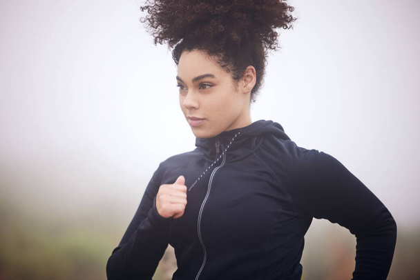 an attractive young female athlete running outside on a foggy morning. - Photo, Image