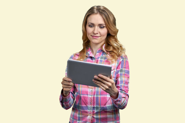 Junge lächelnde Frau blickt auf Tablet-PC. Vereinzelt auf weißem Hintergrund. Hübsches Mädchen mit Videoanruf. - Foto, Bild