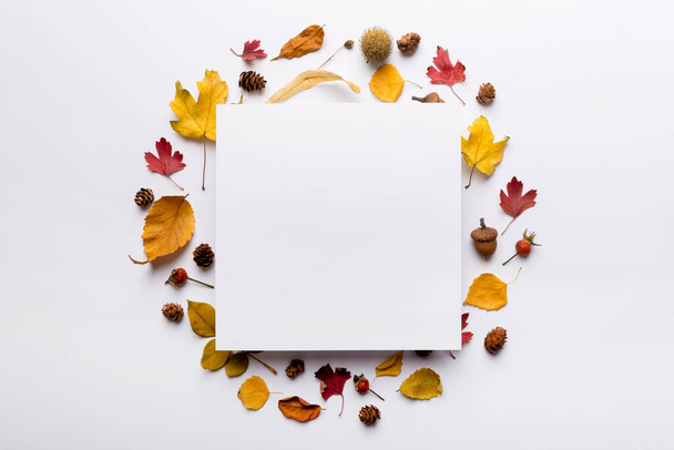 紙のブランクと乾燥した葉をテーブルの上に秋の組成。フラットレイアウト、トップビュー、コピースペース. - 写真・画像