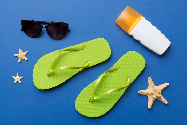 Summer travel concept. Flip flops, sunglasses and starfish on white. Top view on colored background. - Фото, изображение