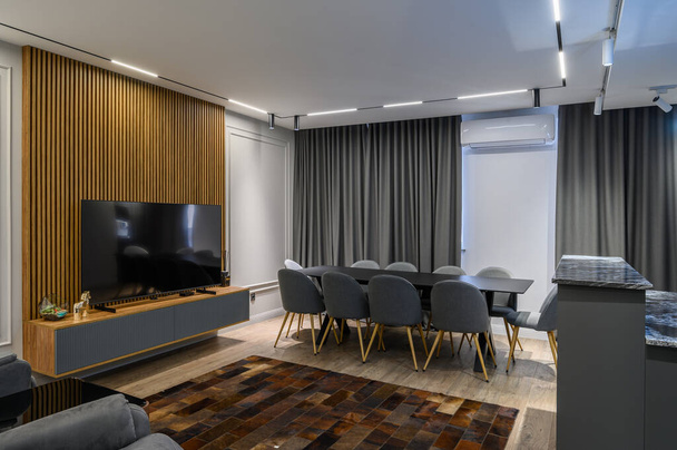 Luxury living room with dining or banquet table and grey kitchen in studio apartment interior - Fotó, kép