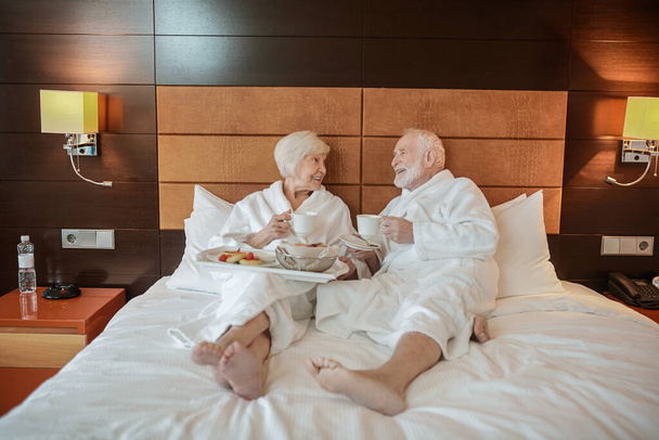 Good time. Senior couple spending weekend in a hotel and looking contented - Foto, afbeelding