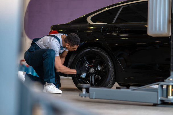 Car inspection. Auto repair worker checking the wheel of the car - Valokuva, kuva