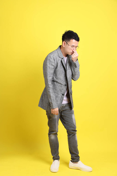 The Asian LGBTQ man with grey blazer standing on the yellow background. - Foto, Imagen
