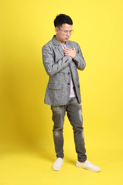 The Asian LGBTQ man with grey blazer standing on the yellow background. - Zdjęcie, obraz