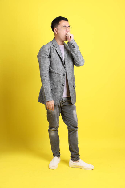 The Asian LGBTQ man with grey blazer standing on the yellow background. - 写真・画像