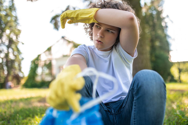 Tired. Cute young volunteer looking tired after gathering garbage - 写真・画像