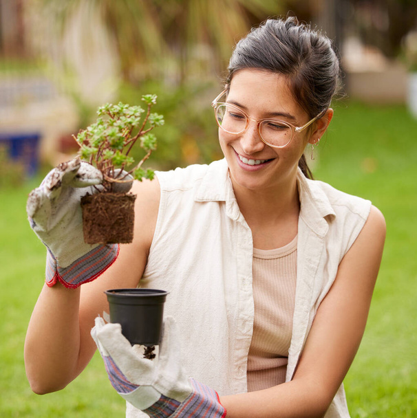 молода жінка, що щасливо тримає рослину, займаючись садівництвом на задньому дворі
. - Фото, зображення