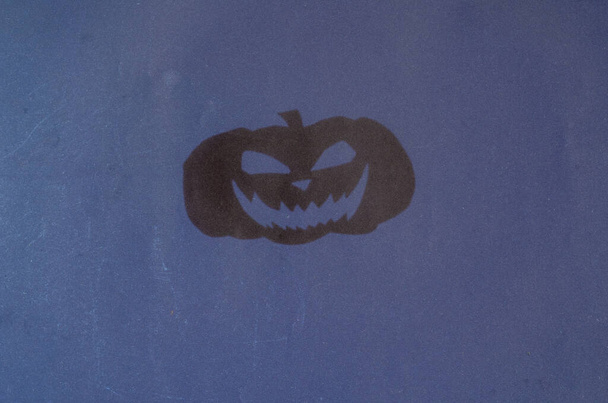 Cień dyni Halloween na szarej ścianie. Sprzęt halloweenowy jest wycięty nożyczkami z kartki papieru. Sylwetka uśmiechniętej onieśmielającej twarzy - Zdjęcie, obraz