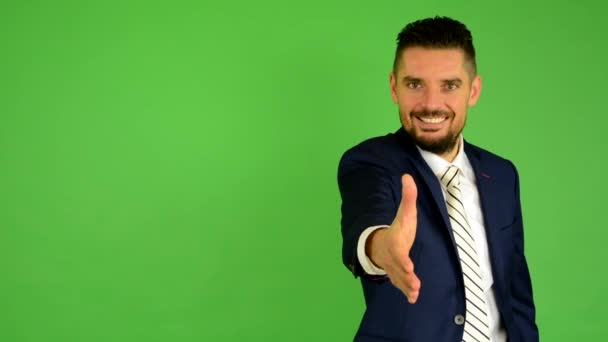 Business man gives a hand in greeting and smiles - green screen - studio - Footage, Video