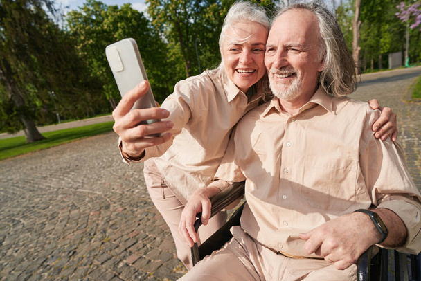 Positive Frau lächelt in die Kamera, während sie ein Foto mit ihrem Partner macht - Foto, Bild