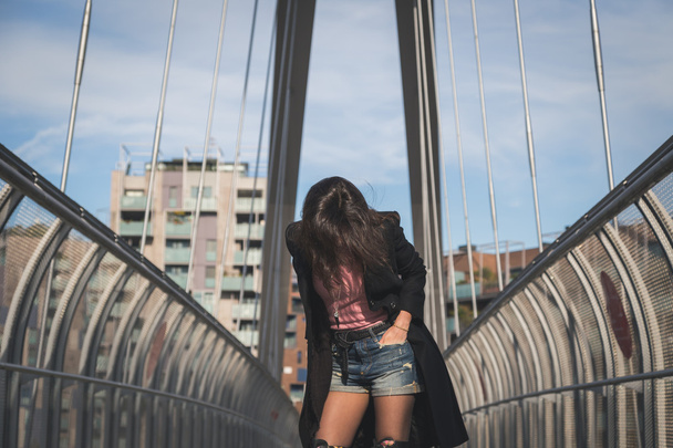 Beautiful young brunette posing on a bridge - Фото, изображение