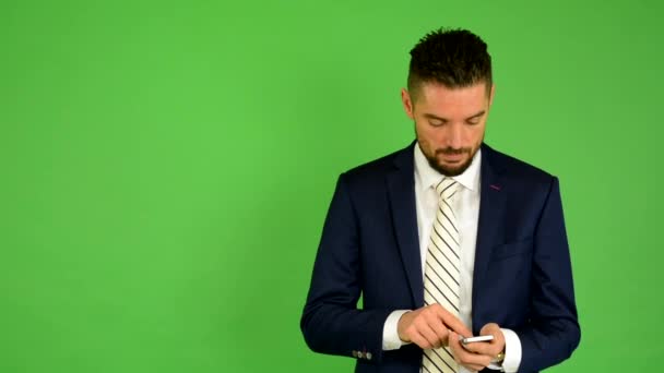 Business man works on phone and smiles - green screen - studio - Footage, Video