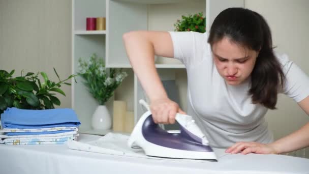 Eine Hausfrau streicht kaum über eine Babywindel. Schlechtes Bügeleisen und schwieriges Bügeln - Filmmaterial, Video