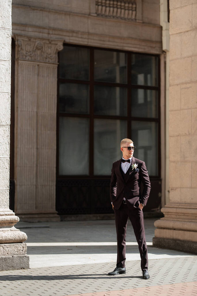 portrait of the groom in a brown three-piece suit with a bow tie on the wedding day - Foto, Imagen
