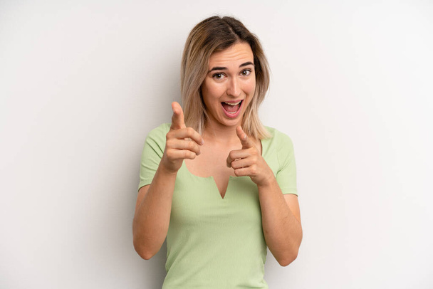 young adult blonde woman smiling with a positive, successful, happy attitude pointing to the camera, making gun sign with hands - Foto, imagen