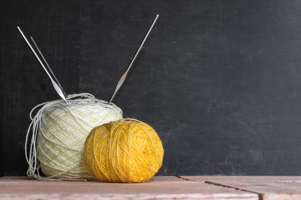 rolls of yellow and white wool yarn, ready to start crocheting, placed on a black and orange wooden background, roll of yarn with three steel crochet hooks. space to copy text - Photo, image