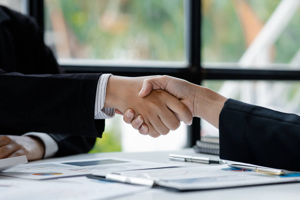 Κοντινό πλάνο δύο επιχειρηματίες κρατώντας το χέρι, Δύο επιχειρηματίες συμφωνούν για τις επιχειρήσεις μαζί και χειραψία μετά από μια επιτυχημένη διαπραγμάτευση. Χειραψία είναι ένας δυτικός χαιρετισμός ή συγχαρητήρια. - Φωτογραφία, εικόνα