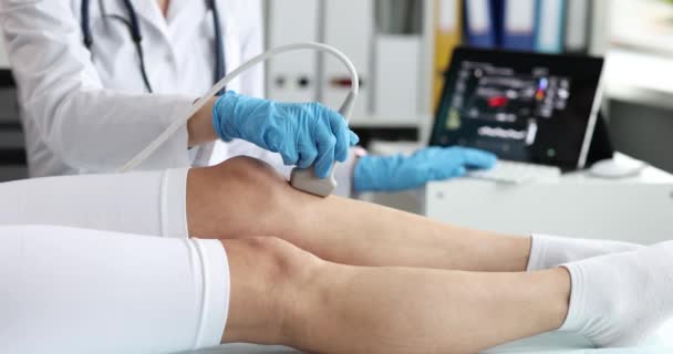 Lekarz robi USG stawu kolanowego kobiecie używając ultrasonografu w klinice. Ból kolana powoduje diagnozę i koncepcję leczenia - Materiał filmowy, wideo