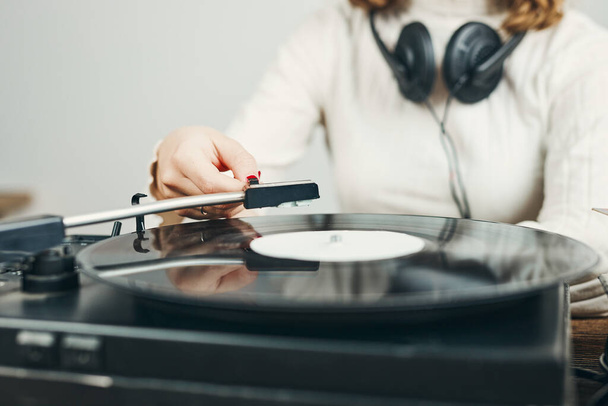 Young woman listening to music from vinyl record player. Playing music on turntable player. Female enjoying music from old record collection at home. Stack of analog vinyl records. Retro and vintage music style. Music Passion and hobby - Foto, Imagem