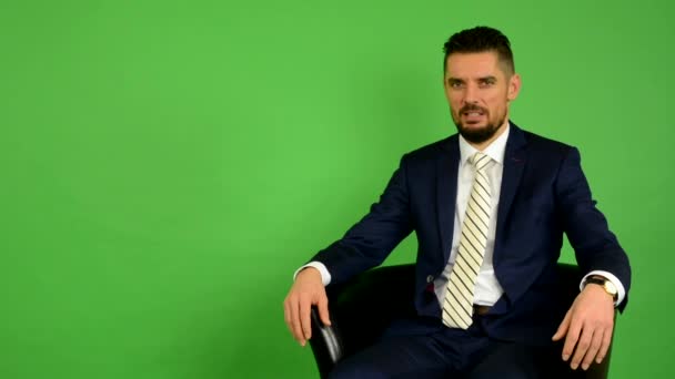 Hombre de negocios se sienta y habla con la cámara (entrevista) - pantalla verde - estudio
 - Imágenes, Vídeo