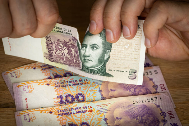 Peso argentino, Crollo finanziario, Valuta preziosa, Mani strappando denaro, Concetto finanziario, Aumento dell'inflazione, Economia bancaria - Foto, immagini