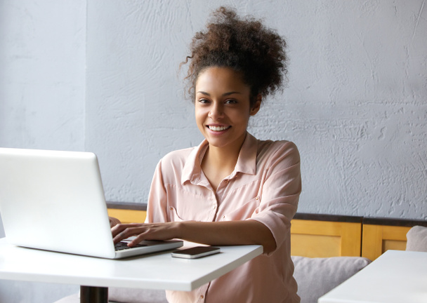 Sorrindo jovem mulher negra trabalhando no laptop
 - Foto, Imagem