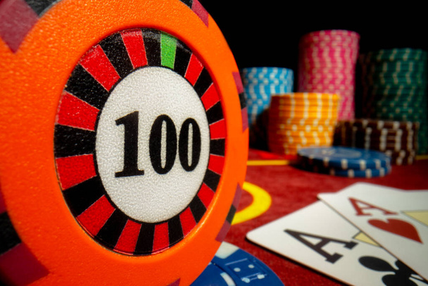 Chip de casino com denominação de cento e dois ases na mesa de casino vermelho em fundo isolado preto. Cartas e fichas para jogar poker, bridge, blackjack. Fundo de jogo. O conceito de - Foto, Imagem