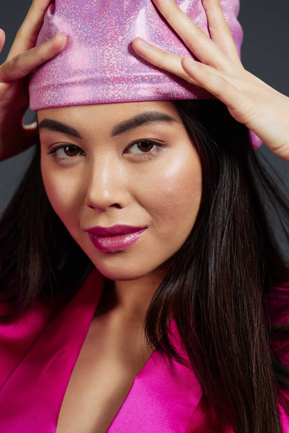 ピンクのミニドレスピンクのヘッドスカーフの豪華なクローズアップグレーのバックグラウンドで美しい女性. 高品質の写真 - 写真・画像