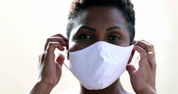 African woman putting covid face mask, black ethnicity female looking at camera - Foto, Imagen