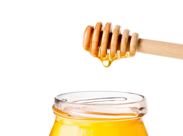 pot de miel ouvert sur fond blanc avec trempette de miel en bois sur le dessus avec du miel de goutte
 - Photo, image