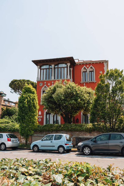 Venice, Italy - May 22, 2022: Row of cars parked in front of a traditional colorful residential building on Lido Island, a barrier island in Venetian Lagoon famous for its Film Festival. - Valokuva, kuva