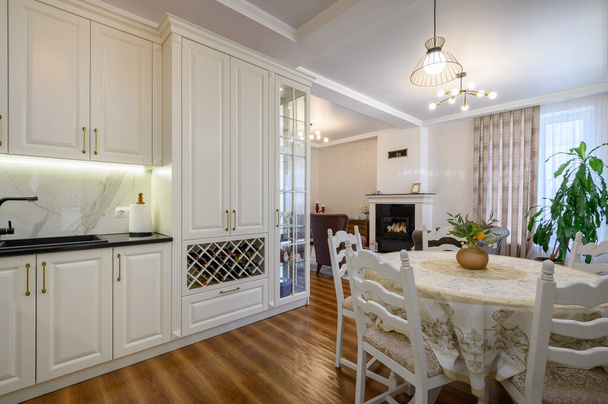 Moderne klassieke grote wit gekleurde luxe keuken en eetkamer in studio appartement interieur - Foto, afbeelding