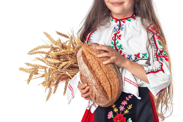 Portrait of a beautiful girl woman in traditional Bulgarian folklore dress holding homemade bread and golden wheat - Fotó, kép