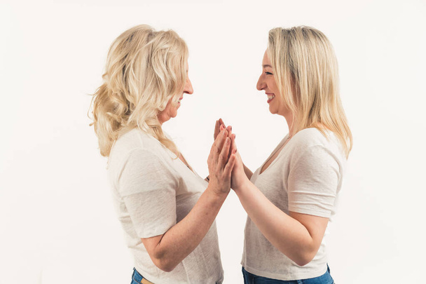 Дві зрілі жінки середнього віку стоять один до одного, торкаючись один одного лобами і тримаючись за руки. Високоякісна фотографія
 - Фото, зображення